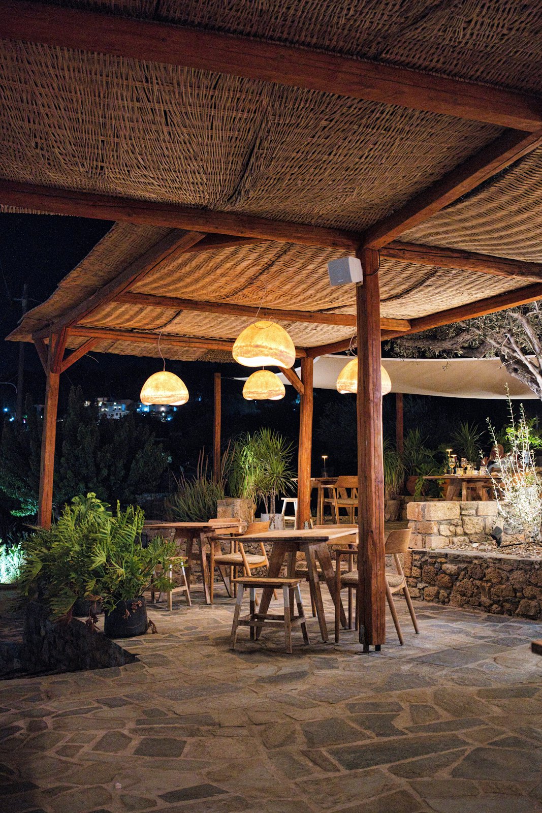 Terrasse mit Laternen und Holztischen am Abend