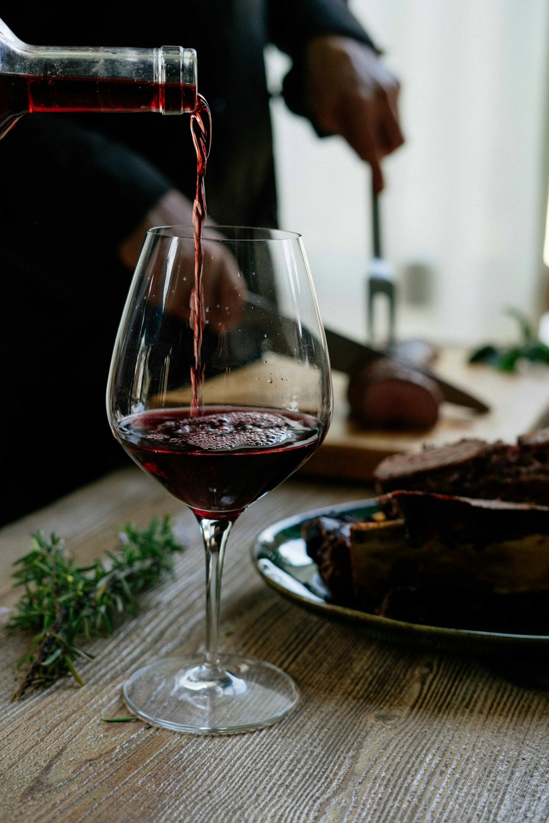 Rotwein wird in ein Glas eingeschenkt